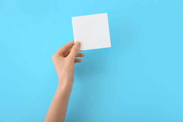 Female hand with blank paper on color background - Foto, Imagen