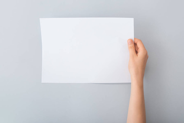 Female hand with blank paper on light background - Photo, Image