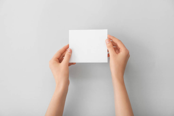 Vrouwelijke handen met blanco papier op lichte achtergrond - Foto, afbeelding