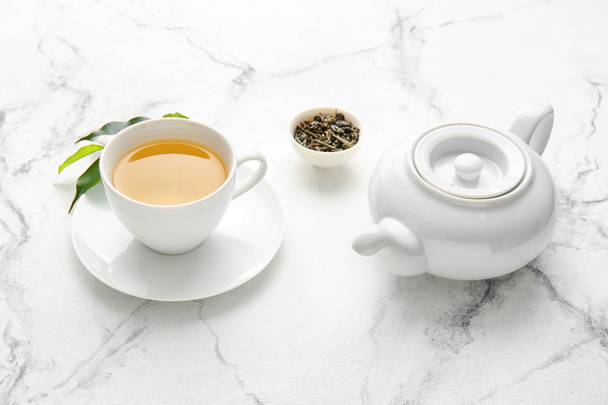Egy csésze zöld tea és teáskanna az asztalon. - Fotó, kép
