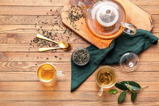 Samenstelling met kopjes groene thee en theepot op houten tafel - Foto, afbeelding