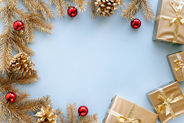 Modré Vánoce nebo nové roky pozadí, prosté složení zlatých vánočních dárků a zlatých jedlových větví s červenými vánočními hračkami, Flatlay, prázdný prostor pro uvítání text.Vánoční koncept. - Fotografie, Obrázek