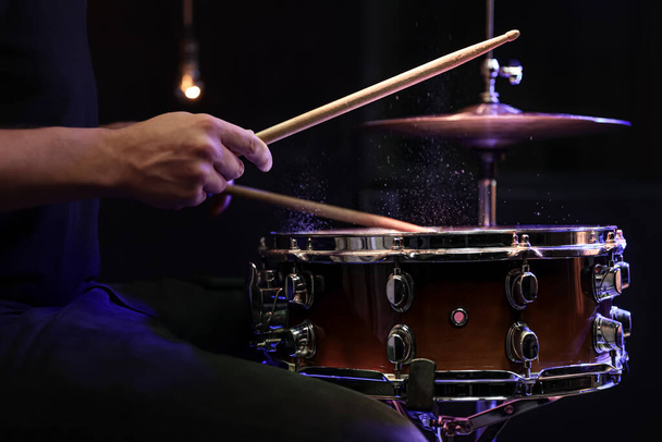 Drum sticks hit snare drum with splashing water on black background κάτω από φωτισμό studio close up. - Φωτογραφία, εικόνα