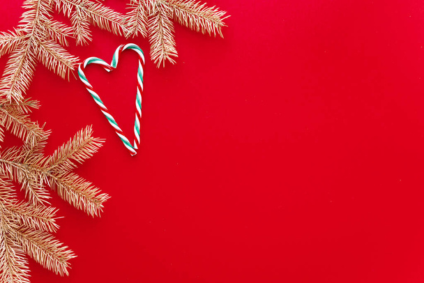 Red Christmas or new year background,simple composition of Golden fir branches and christmas toys,Flatlay,empty space for greeting text. - Foto, imagen
