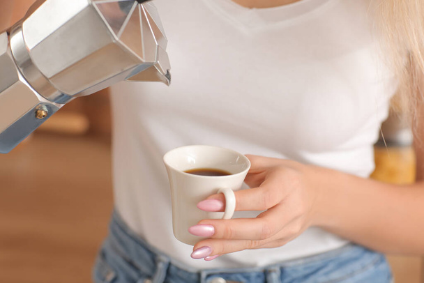 Όμορφη νεαρή γυναίκα πίνει ζεστό καφέ στην κουζίνα, κοντινό πλάνο - Φωτογραφία, εικόνα