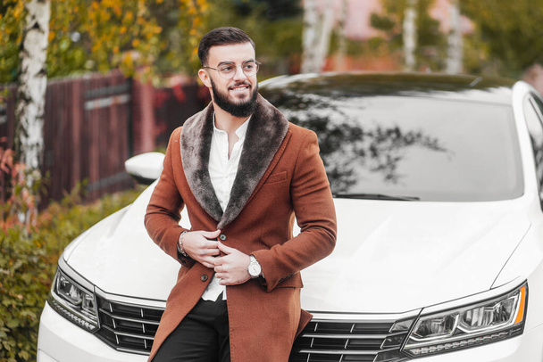 Handsome young man in autumn coat near his car. Rich man. - Zdjęcie, obraz