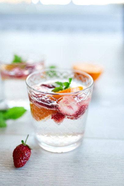 Summer cocktail με φράουλα, πορτοκάλι και μέντα σε ποτήρι σε λευκό τραπέζι, σπιτική δροσιστική λεμονάδα, παντς φράουλα, copy space. - Φωτογραφία, εικόνα