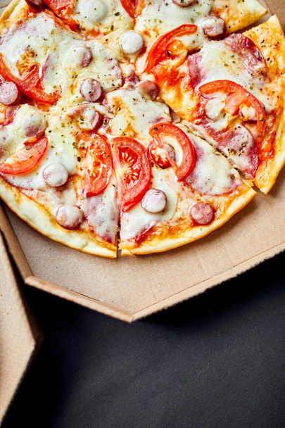 Otwarte pudełko z gorącymi, smacznymi włoskimi plasterkami pizzy na czarnym tle - Zdjęcie, obraz