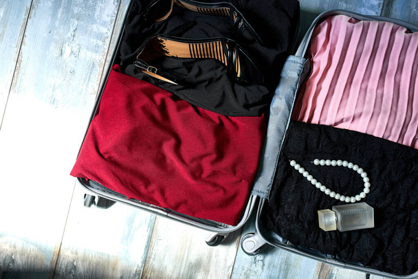 Verpakking koffer thuis met vrouw items, accessoires - Foto, afbeelding