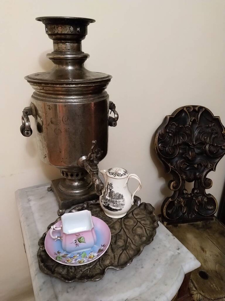 Antik márvány asztal, szamovár, porcelán csésze és csészealj, tejes kanna, fém tálca, fából készült szék faragott háttal - Fotó, kép