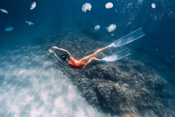 Mujer liberadora con aletas blancas y medusas bajo el agua. Freediving con medusas en el océano azul - Foto, imagen