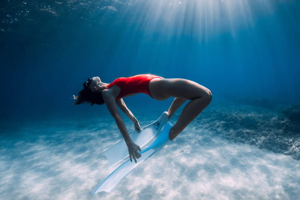 自由な少女は白いフィンで砂浜の海を滑り降りる。フリーダイビングとともに魅力的な女性で青い海 - 写真・画像