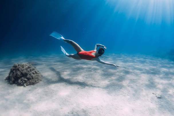 Freediver dziewczyna ślizga się po piaszczystym morzu z białymi płetwami. Freediving z atrakcyjną kobietą w błękitnym oceanie - Zdjęcie, obraz