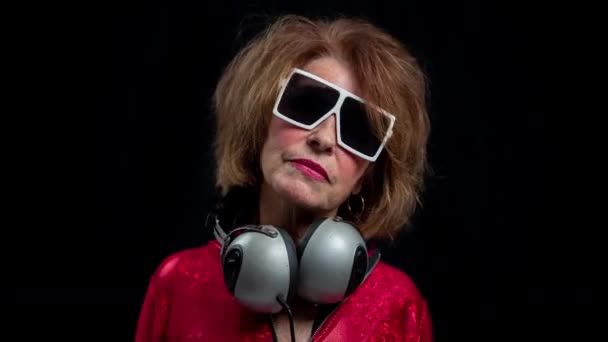 Старшая женщина танцует в дискотеке с наушниками - Кадры, видео