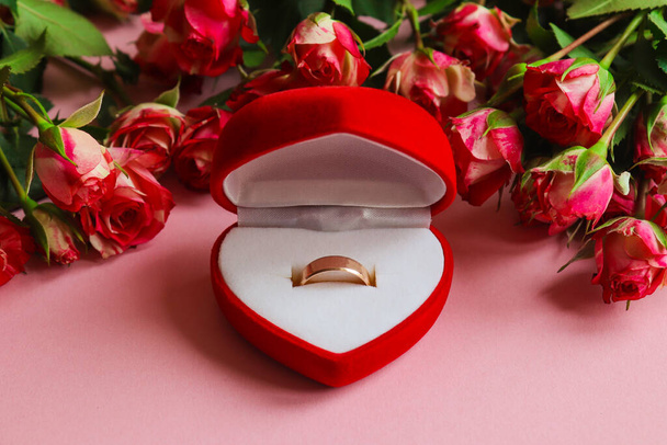 Zlatý snubní prsten v dárkové krabici obklopen květinami. Koncept žádosti o ruku, svatba, láska, Valentýn - Fotografie, Obrázek