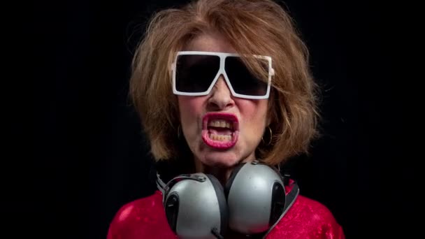 Senior woman dancing in disco with headphones - Záběry, video