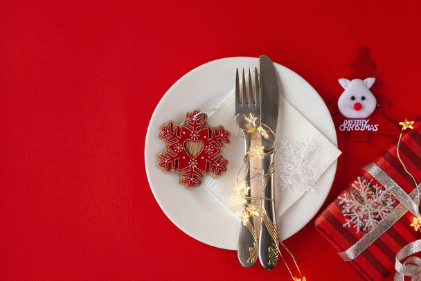 Felszolgált karácsonyi asztal karcos dekoratív szimbólumokkal a piros háttér - Fotó, kép