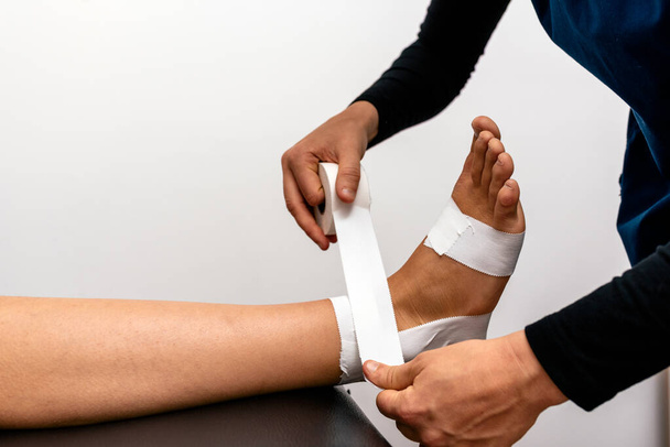 Travailleuse dans une clinique de physiothérapie enveloppant la main des patients avec un bandage. - Photo, image