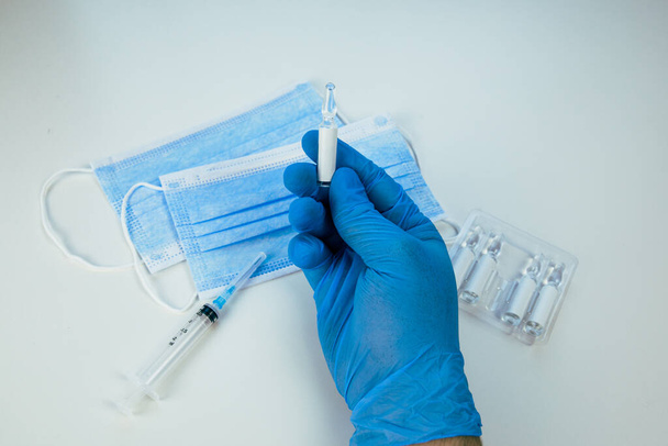 рука в медичних рукавичках тримає ампулу з вакциною
 - Фото, зображення