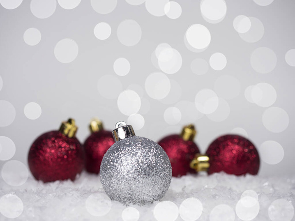 One silver ball on the Christmas tree and four red balls in the back, on a bokeh background, on top there is a place for an inscription. - Photo, Image