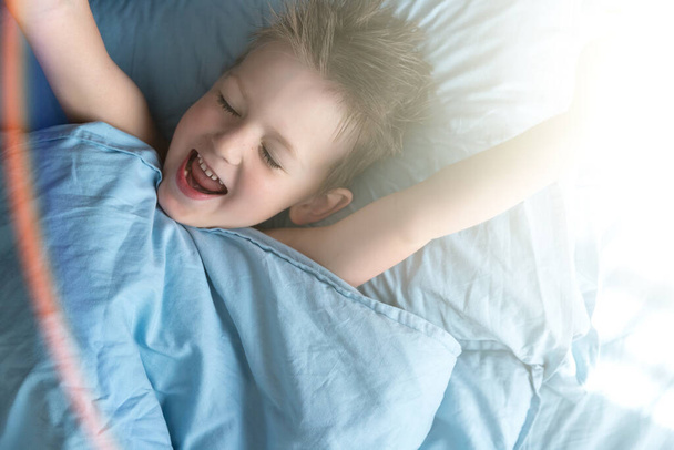Niño feliz en la cama por la mañana. Copiar espacio - Foto, imagen