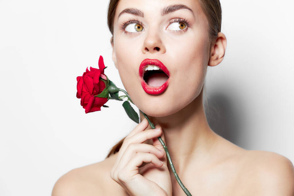 Обнаженные плечи с удивлением смотрят на цветок розы  - Фото, изображение