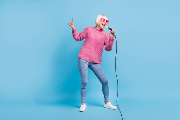 Photo portrait full body view of elderly lady singing pointing finger up holding mic in one hand isolated on pastel blue colored background - Fotó, kép