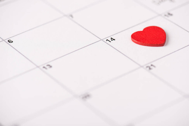 Valentine day celebration concept. Close up view photo of calendar with lying on it red heart on 14th february - Photo, Image