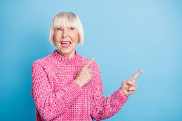 Photo portrait of excited dreamy old lady looking pointing two fingers at blank space isolated on pastel blue colored background - Фото, изображение
