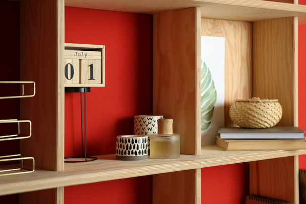 Stylish wooden shelf with decorative elements on red wall - Фото, изображение