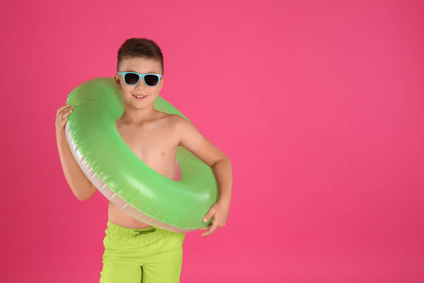 Cute little child in beachwear with bright inflatable ring on pink background. Space for text - 写真・画像