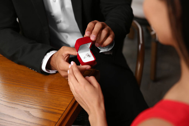 Man with engagement ring making proposal to his girlfriend at table, closeup - Foto, Bild