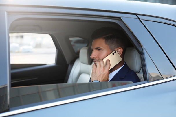 Handsome man talking on phone in modern car - Фото, зображення