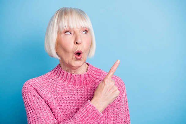 Photo portrait of impressed old woman pointing finger looking at blank space isolated on pastel blue colored background - Photo, Image