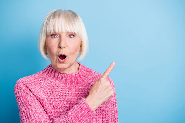 Photo portrait of amazed elderly lady pointing finger at blank space isolated on pastel blue colored background - Fotó, kép