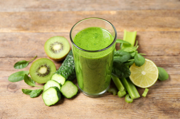 Delicious green juice and fresh ingredients on wooden table - Photo, image