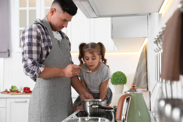 Little girl with her father cooking together in modern kitchen - Foto, Imagem