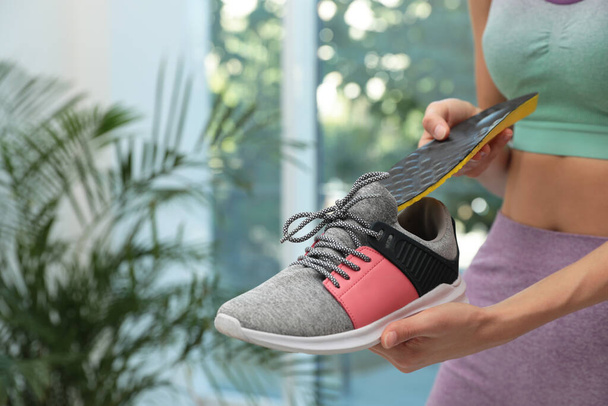 Woman putting orthopedic insole into shoe indoors, closeup. Foot care - Фото, зображення