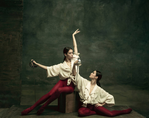 Zwei junge Balletttänzerinnen mögen Duellanten mit Schwertern. Ballett und zeitgenössisches Choreographie-Konzept. Kreatives Foto. - Foto, Bild
