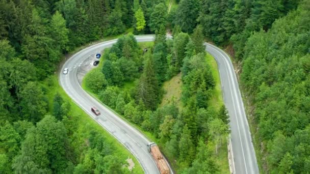 Following from aerial the firewood truck and cars on the road in the mountains surrounded by trees. - Footage, Video