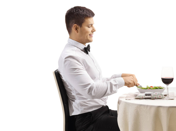 Man eating a salad and at a restaurant table isolated on white background - Fotografie, Obrázek