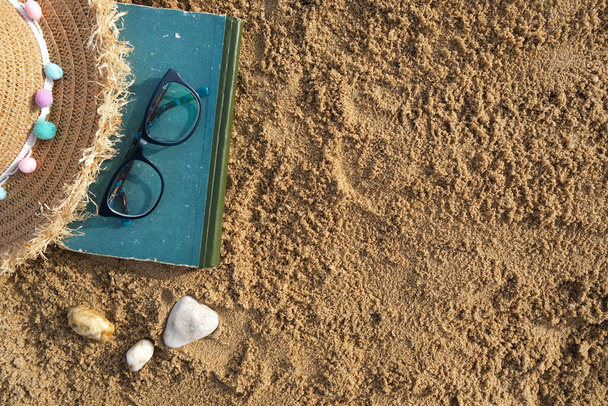beach accessories on the sand. Sunglasses, hat flip-flops and striped hat.  - Fotó, kép