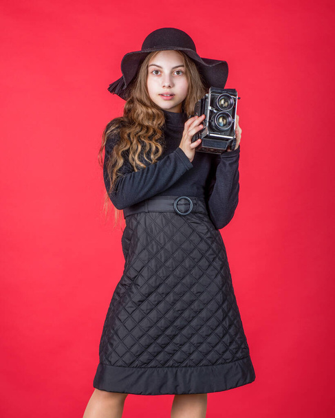retro kid girl in black hat hold vintage photo camera, photographing - Fotó, kép