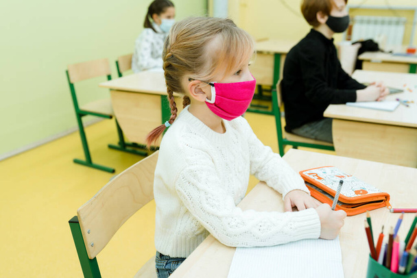 The child is in the lesson in protective equipment. Schooling during a pandemic - Foto, afbeelding