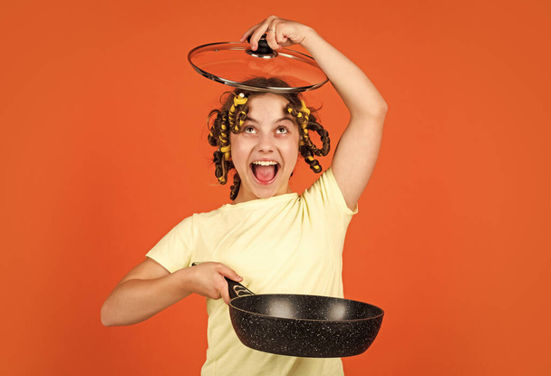 happy childhood. cheerful kid with hair curlers papillotes. housekeeping from childhood. little woman hold pan. cooking in kitchen. concept of household. child cook at home - Foto, Imagem