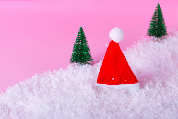 Gorra de Santa Claus y mínimo paisaje de invierno sobre fondo rosa claro. Navidad, Año Nuevo, concepto de invierno. Plano, vista superior, espacio para copiar - Foto, Imagen
