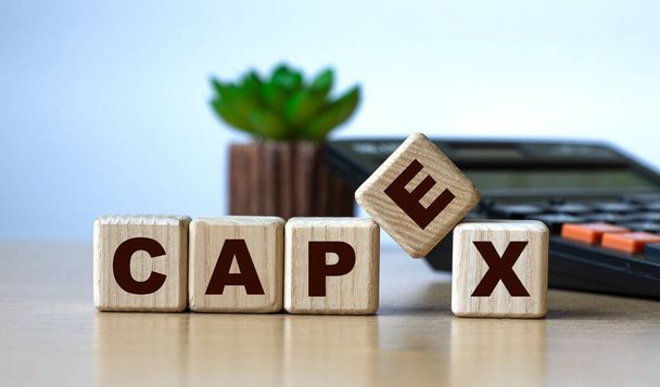 CAPEX - the word on the cubes on the background of the calculator and cactus. Business fnd finance concept. - Φωτογραφία, εικόνα