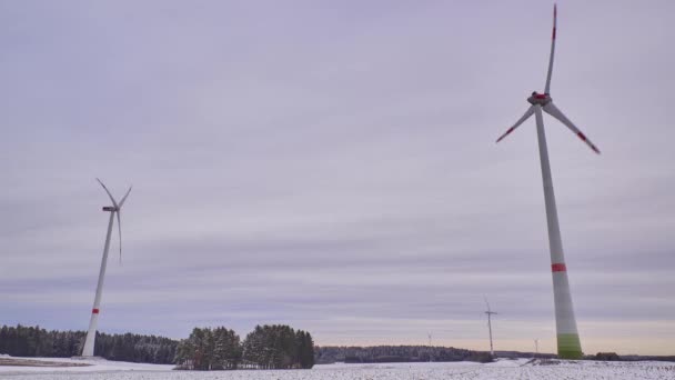 Zeitraffer eines Windparks im Winter. Zeitraffer rotierender Windräder auf einem verschneiten Feld in Deutschland. - Filmmaterial, Video