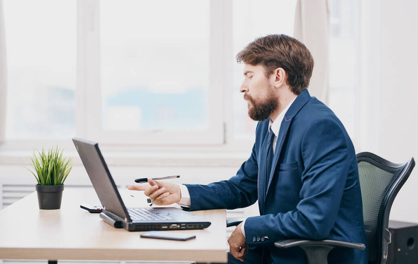 Verbaasde zakenman kijkt naar de laptop aan tafel in het kantoor  - Foto, afbeelding