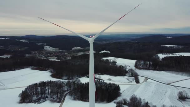 Vista aérea de un aerogenerador en un paisaje invernal. Volando a través de las palas de un aerogenerador. Volando por encima de una turbina eólica. - Metraje, vídeo